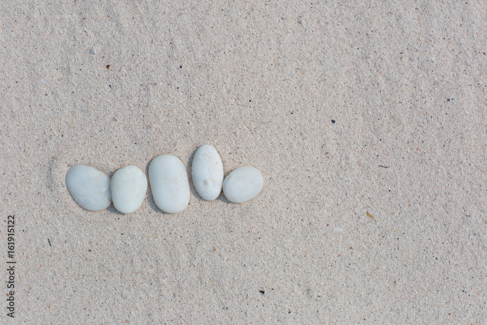 White pebbles, round small stones in a row on dry white sand beach, space for letters or text White pebbles, round small stones in a row on dry white sand beach, space for letters or text