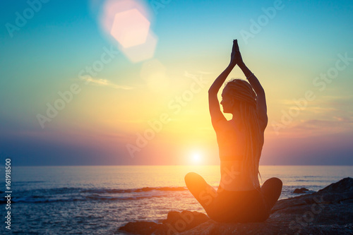Yoga silhouette. Meditation fitness woman on the ocean during amazing sunset. Healthy lifestyle.