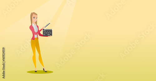 Smiling woman holding an open clapperboard.