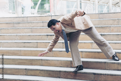 Businessman falling down the steps of staircase photo