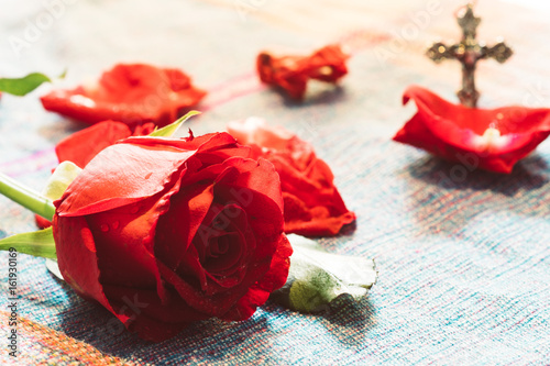 Fotografija Bright Red Rose with blur metal cross god background