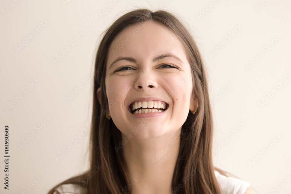 Headshot portrait of laughing young woman. Cheerful teen girl with happy facial expression looking at camera with toothy smile. Female positive emotion, comic situation concept. Close up. Front view Headshot portrait of laughing young woman. Cheerful teen girl with happy facial expression looking at camera with toothy smile. Female positive emotion, comic situation concept. Close up. Front view