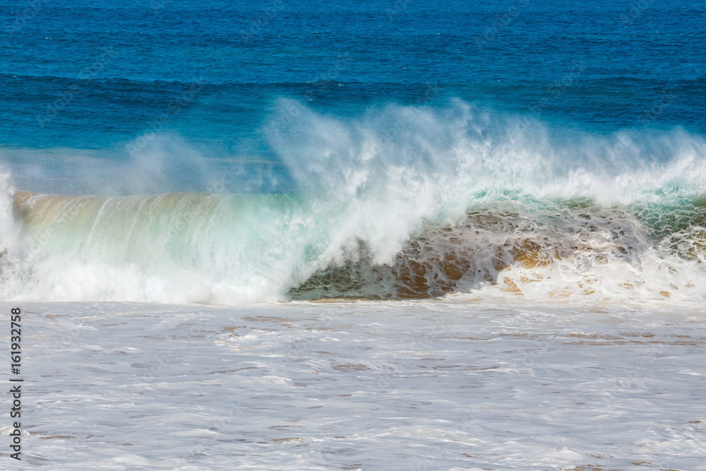 blue wave crashes down at the beach in El Cotillo village in Fuerteventura island, Spain blue wave crashes down at the beach in El Cotillo village in Fuerteventura island, Spain