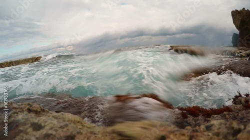 Turquoise Waves Strike Rocky Coast With Seaweeds Cloudy Sky Mediterranean Sea photo