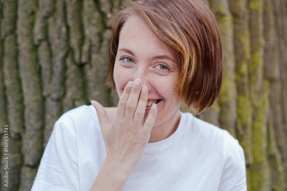 Laughing woman in white shirt with red hair over tree. Laughing woman in white shirt with red hair over tree.