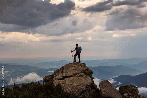 Trekker hiking on a mountain with beautiful storm clouds in background © danmir12