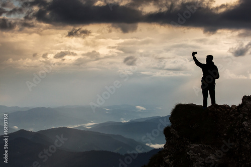 Trekker taking selfie on a mountain with beautiful storm clouds in background