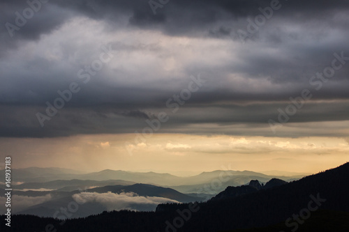 Beautiful sunset over mountains with storm clouds in background. Masivul Ceahlau, Romania.