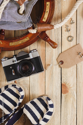 Camera, espadrilles and maritime decorations on the wooden background