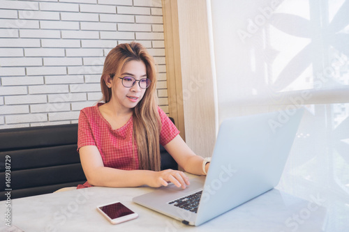 Asian girl working at a coffee shop with a laptop.female freelancer connecting to internet