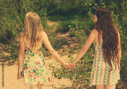 Figures of two young romantic girls wallk in green wood toning photo photo