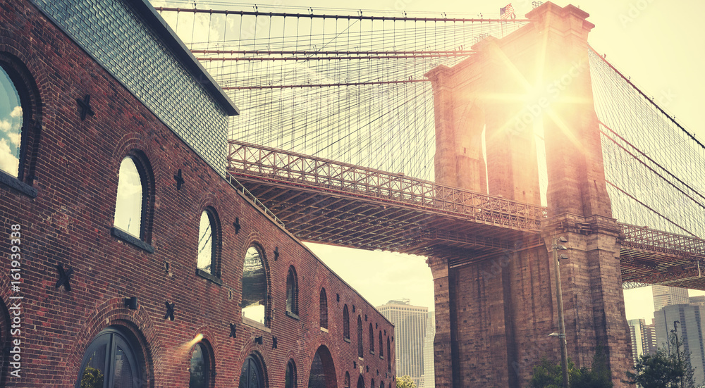 Fototapeta premium Brooklyn Bridge o zachodzie słońca z flary obiektywu, kolorowanie stosowane, Nowy Jork, USA.