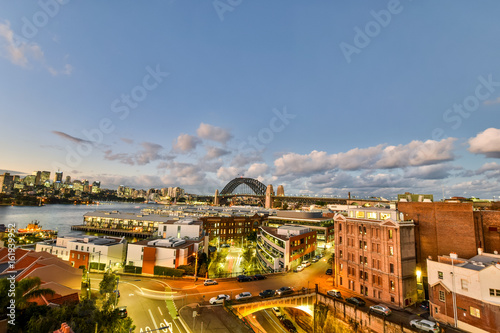 Stunning HDR night shot of the night skyline in Sydney, New South Wales, Australia. Beautiful view of the Sydney Harbour bridge, North Sydney, Millers Point and Walsh Bay. Shortly after sunset.