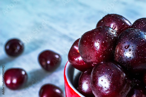 ripe cherry fruits in old style enamel iron jar, photo