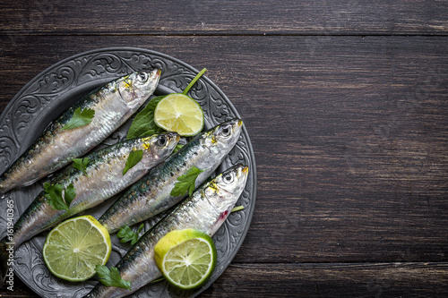 Close up of sardine fish with lime slice on wooden table photo