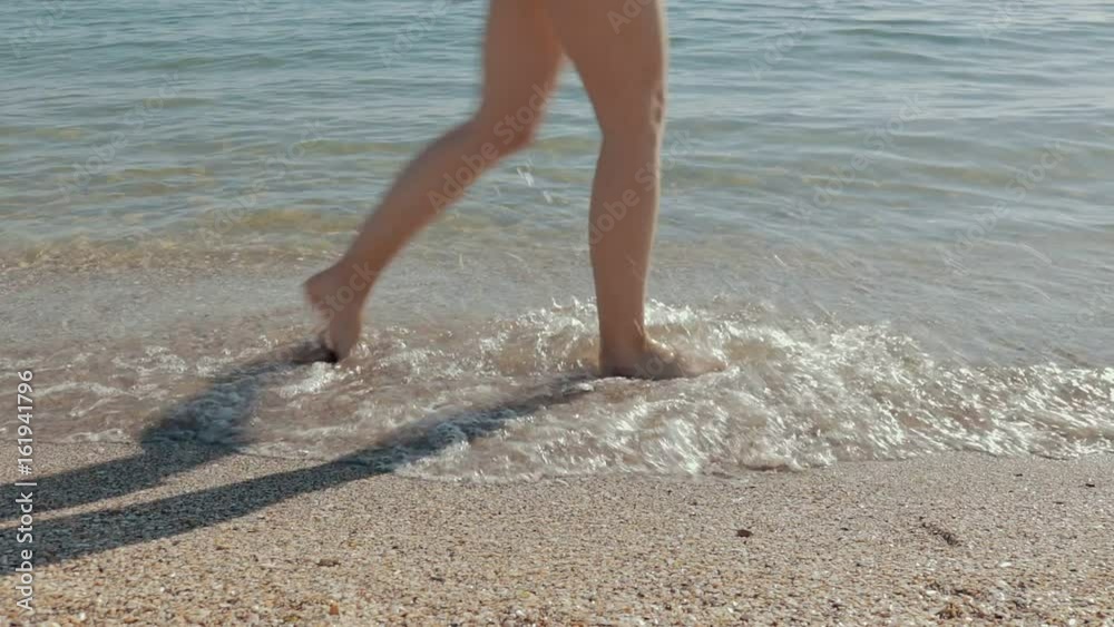 Close-up of female legs walking along the beach, slow motion Close-up of female legs walking along the beach, slow motion