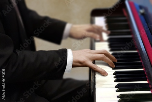 Man in black suit playing piano