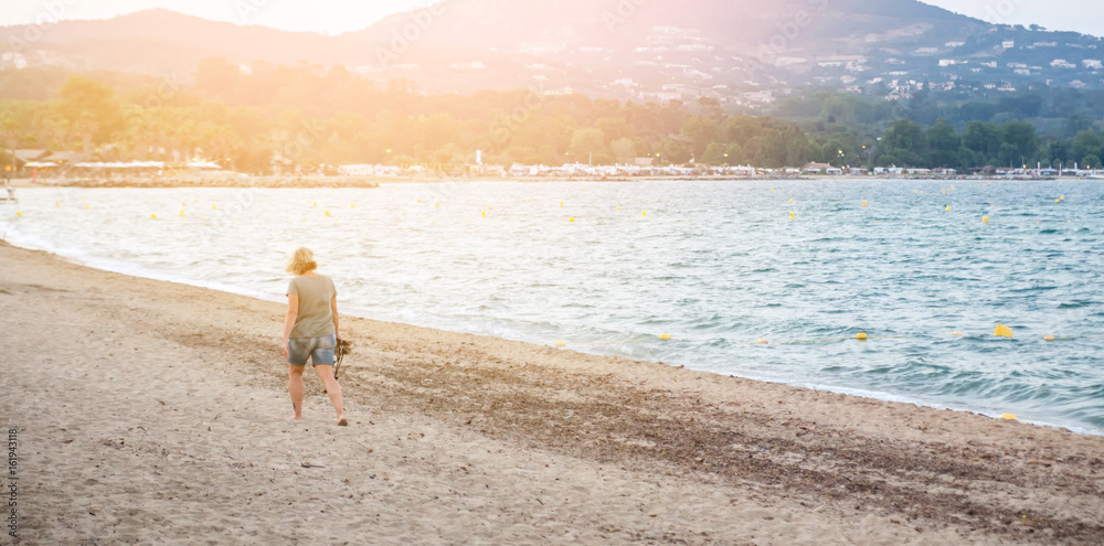 A woman is walking alone on the beach A woman is walking alone on the beach