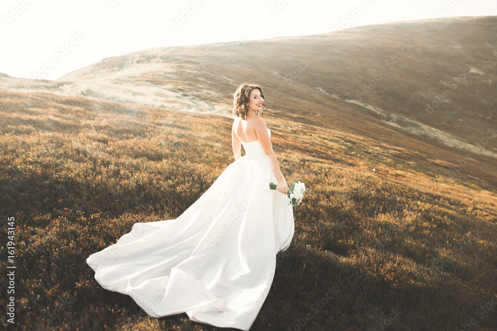 Beautiful bride with a bouquet on mountain background at sunset Beautiful bride with a bouquet on mountain background at sunset