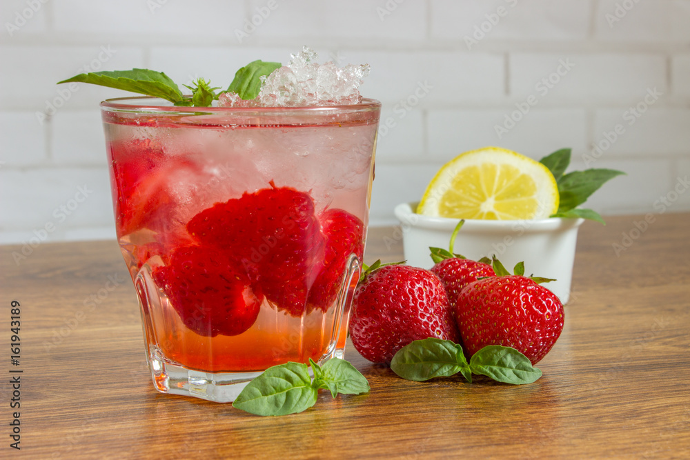 A refreshing summer drink with ice, strawberries and lemon on a wooden background. The concept of fruit drink. A refreshing summer drink with ice, strawberries and lemon on a wooden background. The concept of fruit drink.