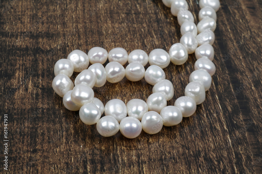White pearls strand on the wooden background White pearls strand on the wooden background