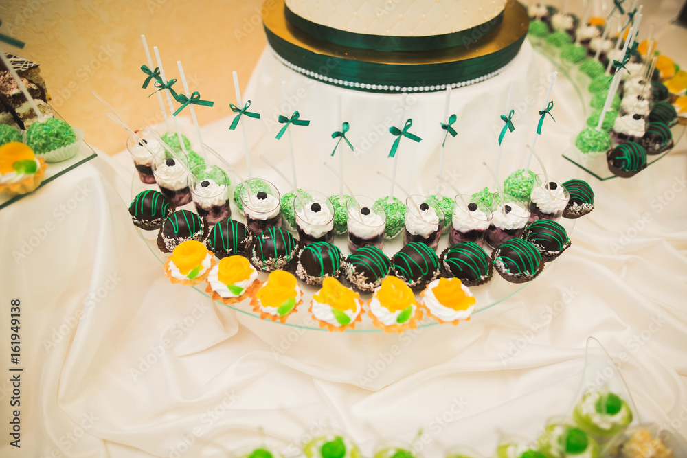 Fototapeta premium Delicious sweets on wedding candy buffet with desserts, cupcakes