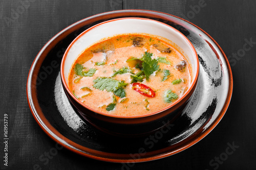 Soup with meat in bowl with oregano, peppers and vegetables on dark wooden background. Homemade food