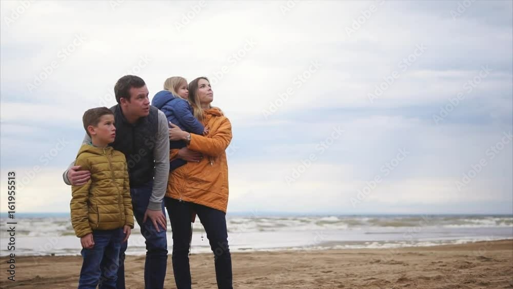 Family standing together on the seashore. Man, woman, boy and girl. Father and son talking and laughing. Family standing together on the seashore. Man, woman, boy and girl. Father and son talking and laughing.
