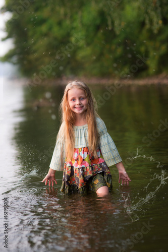 Fototapeta Naklejka Na Ścianę i Meble -  Beautiful fairy girl  with long hair standing in the river in a forest. Fairy girl mermaid in the river