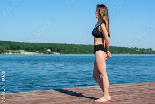Fitness girl on the dock by the lake.
