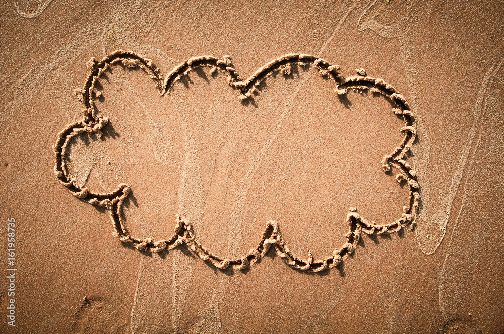 A speech cloud or think bubble drawn out on a sandy beach. Beach background. Top view A speech cloud or think bubble drawn out on a sandy beach. Beach background. Top view