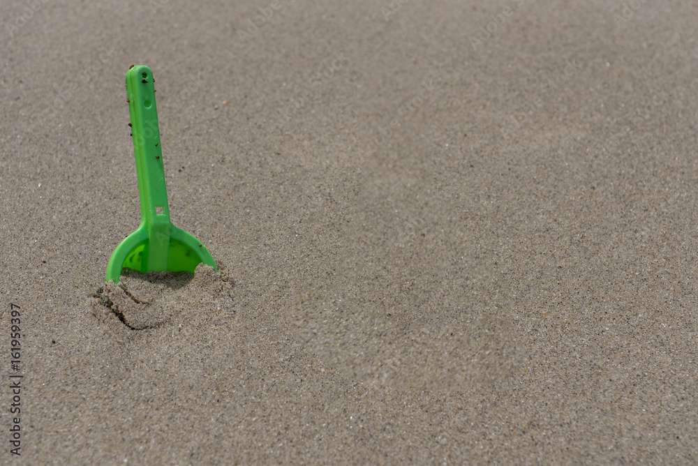 Dirty Green Shovel Digging in Wet Sand