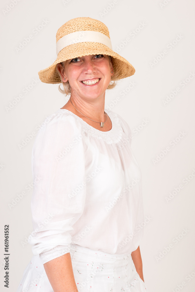 portrait of a attractive blond haired mid aged european woman wearing white dress and a beige summer head showin happy face - half body - studio shot on white background. portrait of a attractive blond haired mid aged european woman wearing white dress and a beige summer head showin happy face - half body - studio shot on white background.