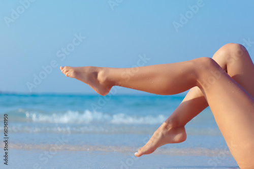 Female legs on blue sea background  side view