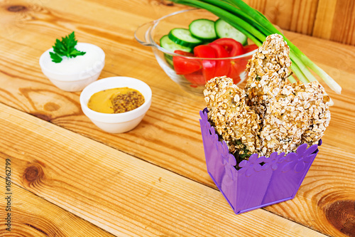 Chicken fillet in oat flakes on wooden background photo