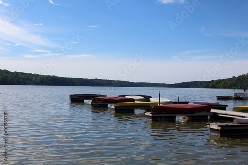 Fototapeta Naklejka Na Ścianę i Meble -  The canoes on the docks at the lake with the forest trees and sky in the background.