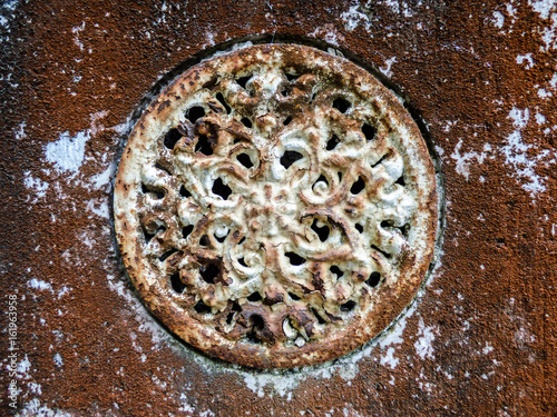 Old and rusty metal air vent on a decaying wall