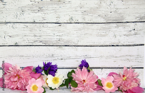 Flowers of pink peony, dogrose and bells near the wooden wall, rustic style, background