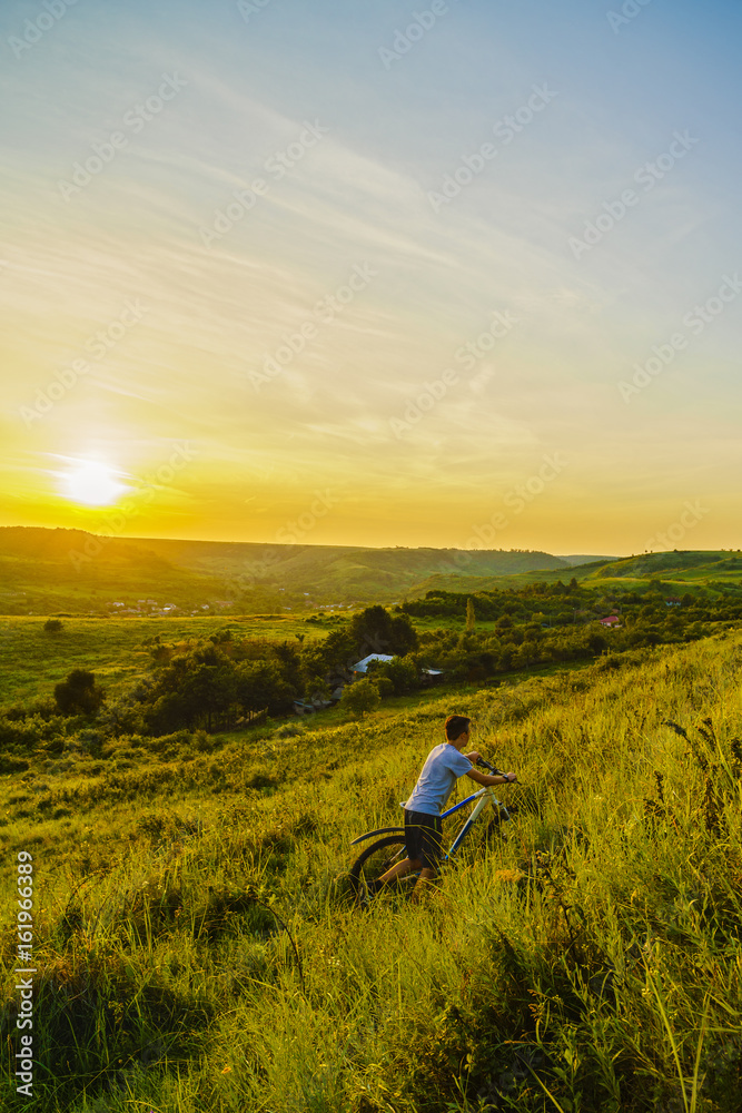 Young boy with a bicycle on a hill