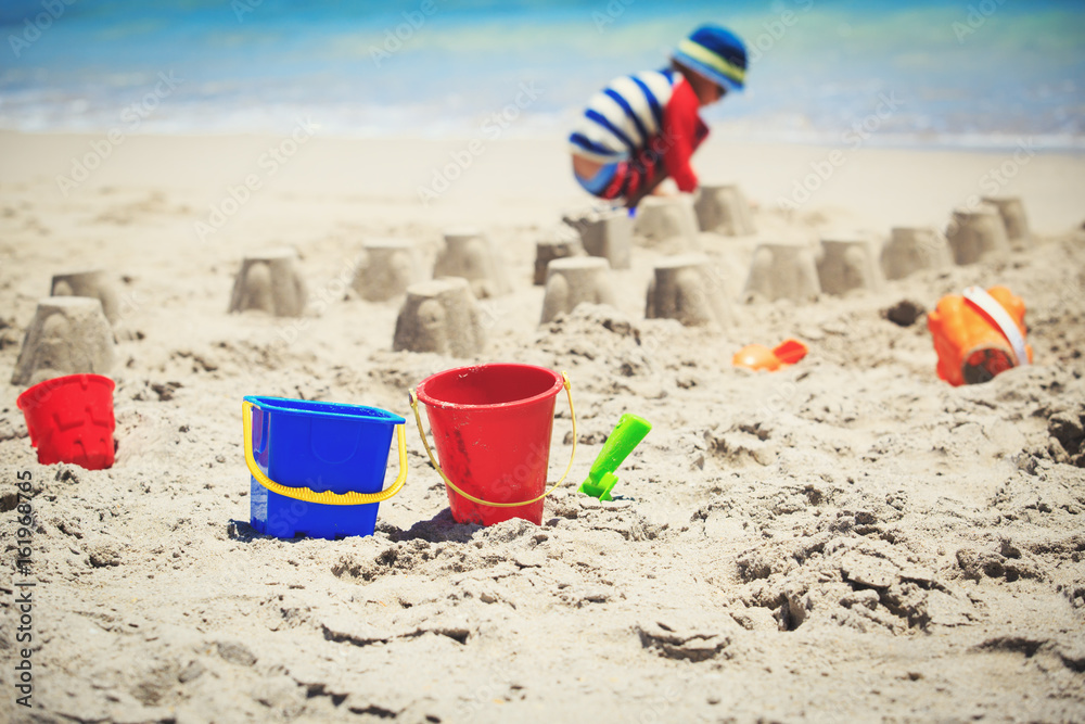 toys and little boy making castle on beach toys and little boy making castle on beach