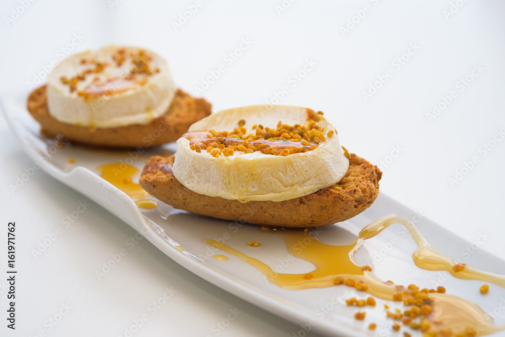  Fresh goat cheese with honey and pollen on the bread, macro, isolated