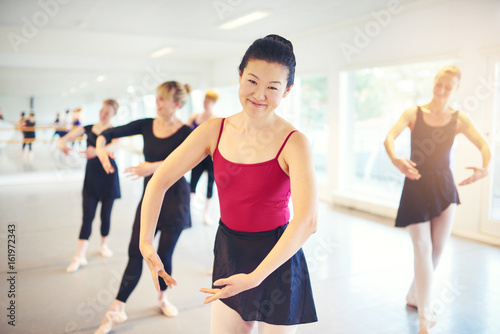 Asian adult woman smiling while performing ballet in class