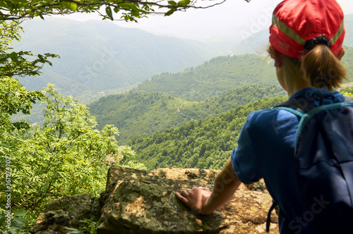 Teen girl looking down from the high cliff 