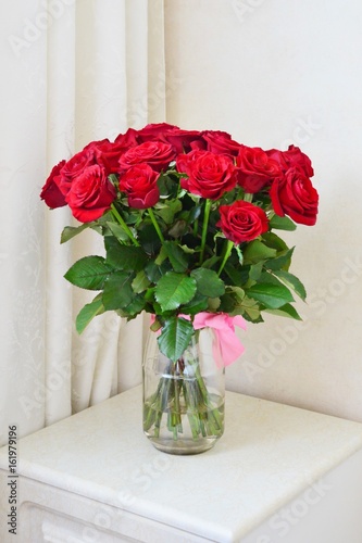 Red roses bouquet  in glass vase on white table