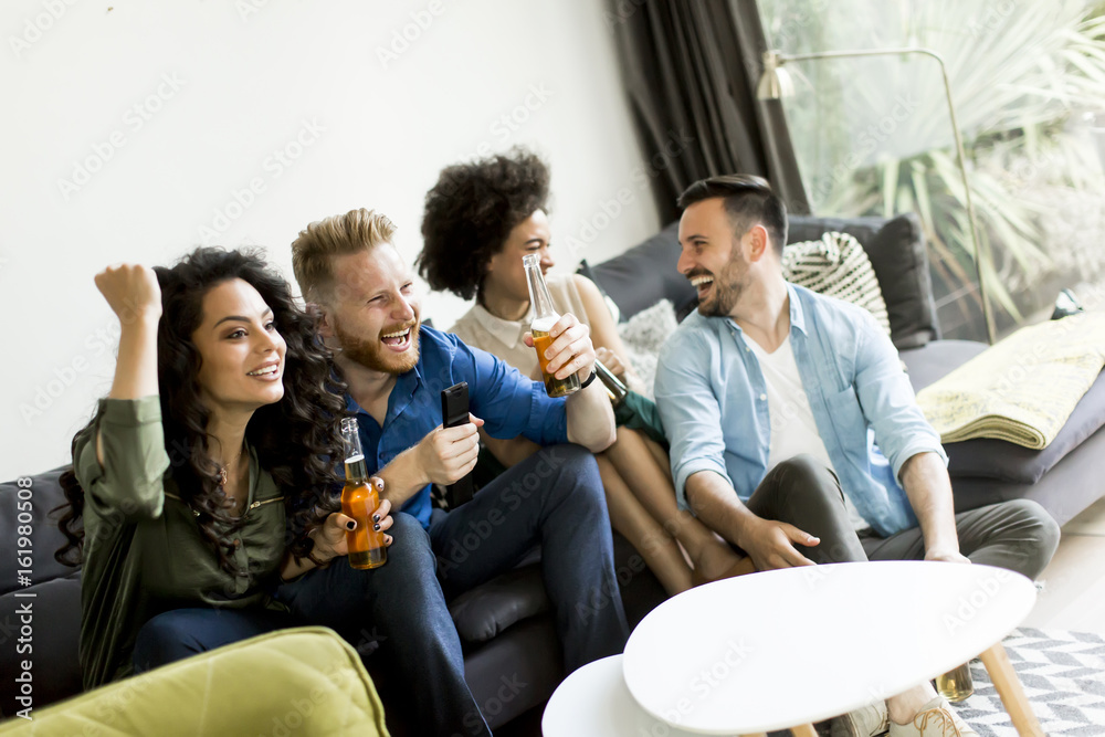 Obraz premium Group of friends watching TV, drinking cider and having fun