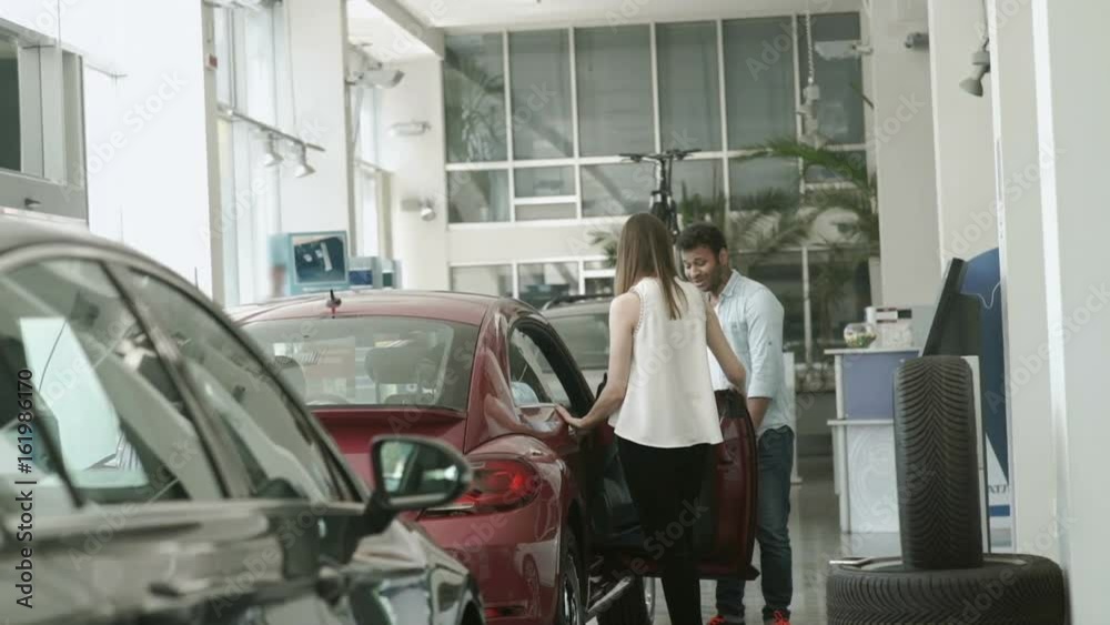 Young couple choose the modern car in car dealership Young couple choose the modern car in car dealership