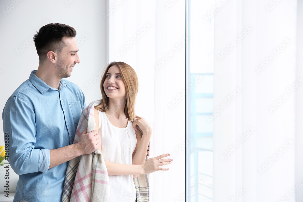 Happy couple standing near big window Happy couple standing near big window