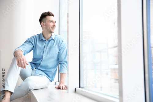 Smiling man sitting on sill...