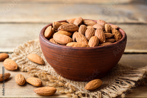 Almonds in ceramic bowl on wooden background