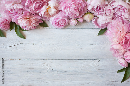 Obraz na plátně Pink flowers peonies and roses on a white wooden background, space for greeting